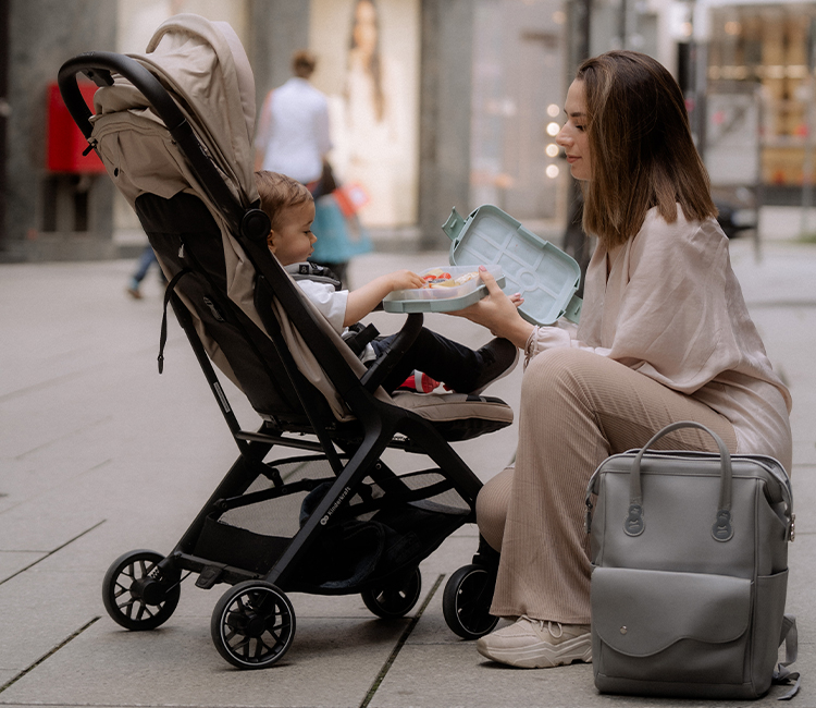 a-mom-giving-her-son-food-in-a-box-while-he-seats-in-a-NUBI-2-stroller